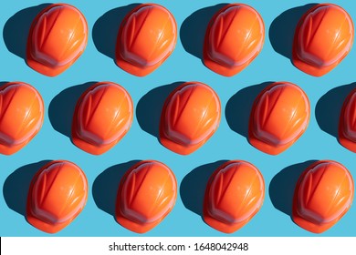 Orange Safety Helmet Rows On A Blue Background With Hard Shadows. Looking From Above.industrial Pattern Backdrop.