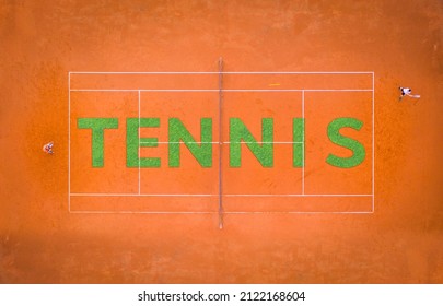 Orange Sand Tennis Court With Two Players Playing From Above With Lettering Made Of Grass