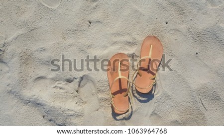 Orange sandals on the sand.