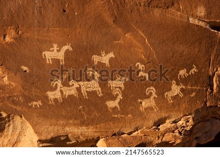 Orange sandstone rock wall with animal petroglyphs in Arches National Park, Utah, United States