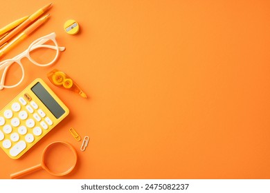 Orange school supplies including calculator, glasses, magnifier, paper clips. Back to school concept, vibrant stationary background - Powered by Shutterstock