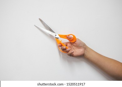 Orange scissors on a white background in the hands woman