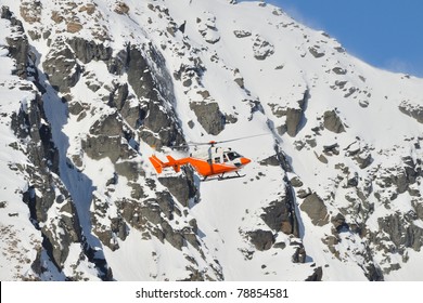 Orange Search And Rescue Chopper Flying In Front Of Very Steep Mountain Slope