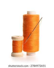 Orange sewing thread spools with needle isolated on white background, closeup