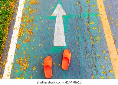 Orange shoe on the way keep moving to forward.  Asphalt road and direction arrow sign. setup to success concept. Choosing your Choices. 