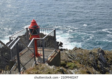 Orange Signal Light On A Rock. Close Up. Bushes On Rocks. Waves On Rocks. Foam. Handrail On The Rocks. Sunny Summer Day. Mizen Head Weather Station. Ireland.