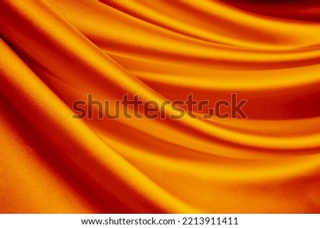 Orange silk satin curtain. Bright luxury background for design. Soft folds. Shiny golden draped fabric. Wavy lines. Flowing. Fluid, liquid, ripple effect. Valentine, Mother's day, festive. Fiery.