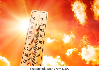 Orange sky with bright sun and thermometer symbolizing climate change and global warming - Shutterstock ID 1739481500