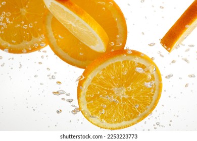 Orange slices dropping or falling in clear water with bubbles over a white background. - Powered by Shutterstock