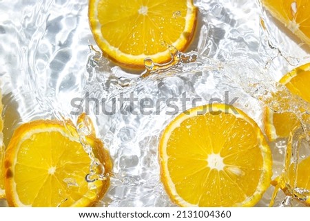 Orange slices in water on a white background. Orange slices fall into the water. Refreshing citrus fruit