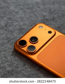 Orange Smartphone Camera Module Close Up on Gray Textured Surface