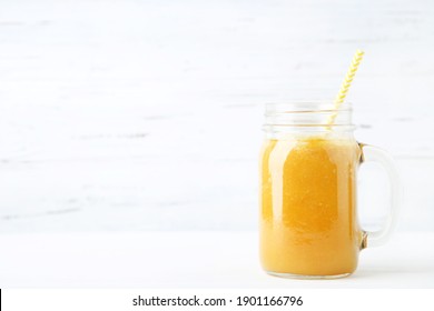 Orange Smoothie In Glass Jar On White Wooden Background