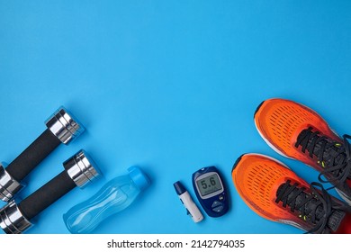 Orange Sneakers, Metal Dumbbells, A Plastic Bottle With Drinking Water And A Glucometer On A Blue Background. Exercise To Overcome Insulin Resistance