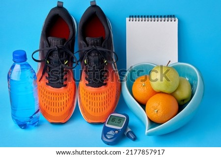 Orange sneakers, a notebook diary, a glucometer, a bottle of drinking water and fruits. Concept of a healthy lifestyle to maintain normal blood glucose levels. Blood glucose control