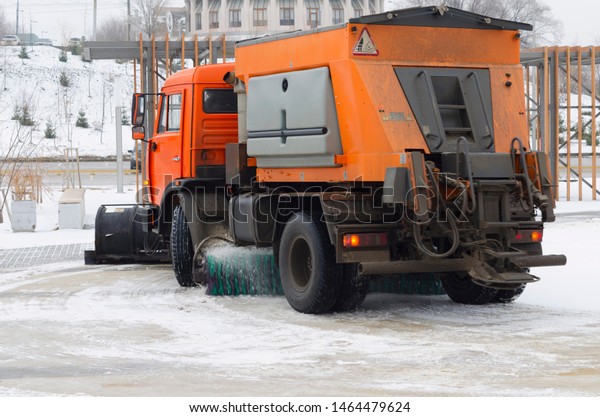 Orange snow\
plow cleans the road from\
snowdrifts