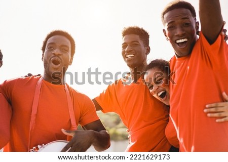 Orange sport fans screaming while supporting their team - Football supporters having fun at competition event - Soft focus on center guy face