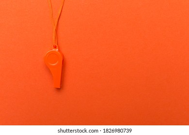 Orange sports whistle on orange background.Concept- sport competition, referee, statistics, challenge. Basketball, handball, futsal, volleyball, soccer, baseball, football and hockey referee whistle
