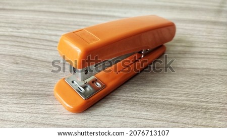 Orange stapler isolated on wooden table