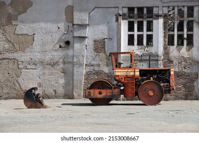 Orange Steamroller In Front Of An Old Industrial Building