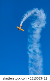 orange stunt plane taking a nosedive against blue sky with smoke trail at Avalon airshow - Shutterstock ID 1315083422