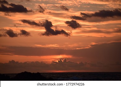 Orange Sun Setting With A Cloudy Sky.