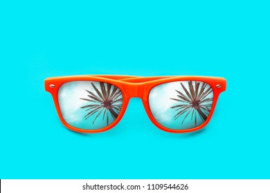 Orange Sunglasses With Palm Tree Reflections Isolated In Intense Cyan Blue Background. Minimal Image Concept For Ready For Summer, Sun Protection, Hot Days And Tropical Travel Vacation.