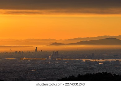 Orange sunrise glow between cloud and smog over sprawling city