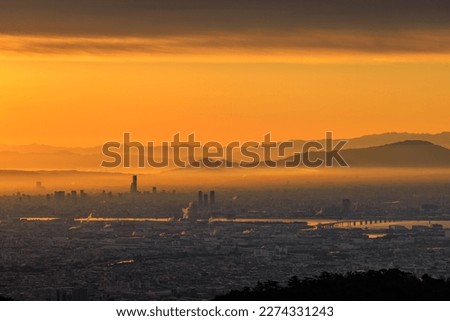 Orange sunrise glow between cloud and smog over sprawling city