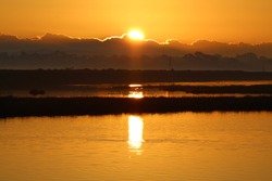 Orange Sunrise In The Morning Over Water At Bolsa Chica Ecological Reserve California, USA