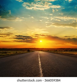 Orange Sunset In Clouds Over Asphalt Road