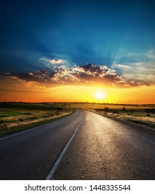 orange sunset in low dramatic clouds over asphalt road