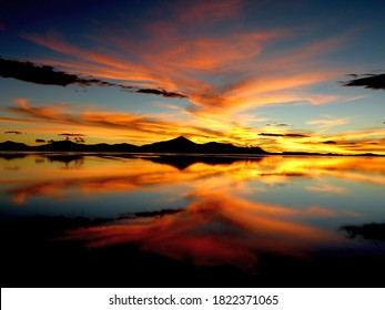 Orange sunset over salt lake in desert Scenic sky clouds reflection in water, Impressive golden nightfall, Spectacular night landscape, Colored heaven Salt flats Uyuni, Altiplano, Gold bright sundown