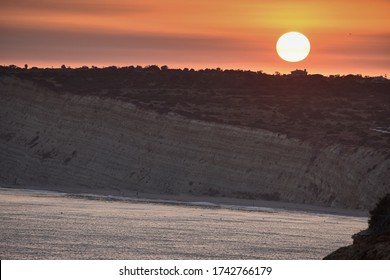 An Orange Sunset Sky Over A Cliffed Coast