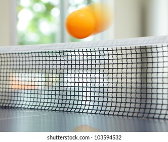 Orange Table Tennis Ball Moving Over Net On Blue Table