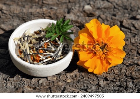 Orange tagetes flower with seeds and leaves in a small bowl 