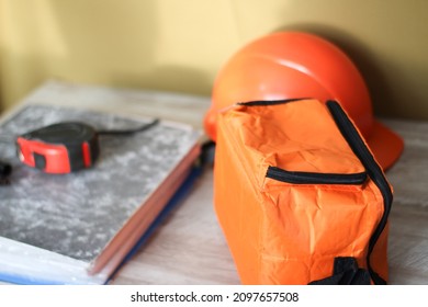 orange tool bag yardstick calipers and construction helmet on a table