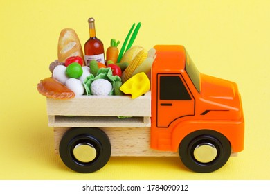 An Orange Toy Truck Delivering Grocery Food  In A Wooden Box. Food Supply Concept.