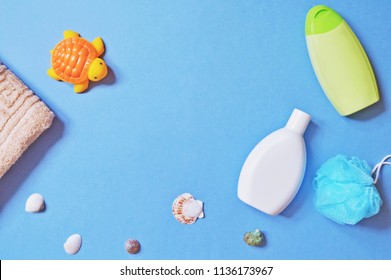 Orange Toy Turtle, Terry Towel, Baby Shampoo, Shower Gel And Seashells On A Blue Background. Photo View From Above. Bathroom Things