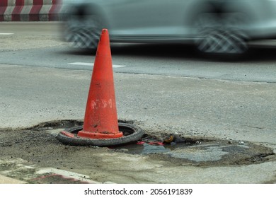 Orange Traffic Cone  Placed On A Bumpy Road Surface.  So That The Car Traveling Can See The Symbol Clearly To Prevent Accidents  Blur Background