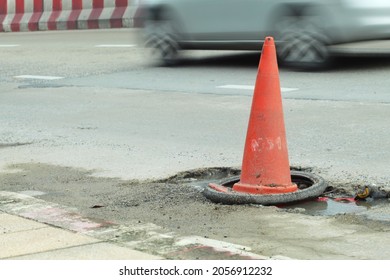 Orange Traffic Cone  Placed On A Bumpy Road Surface.  So That The Car Traveling Can See The Symbol Clearly To Prevent Accidents  Blur Background