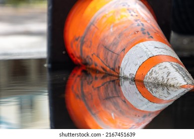 Orange traffic cone submerged in water on flooded road after heavy rain storm
