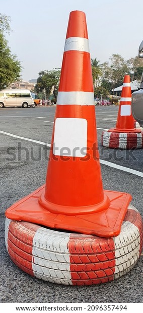  An\
orange traffic cone with white stripes is stacked on old tires\
painted red-white to define parking boundaries or routing traffic\
on the road.Traffic safety is sign street\
outdoor.\
