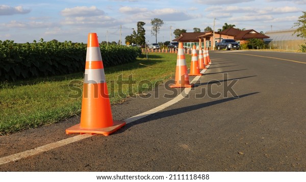 Orange traffic cones on the road. A large number of\
traffic cones were placed on the road in the afternoon for safety\
and protection against a white cloudy sky background. Selective\
focus