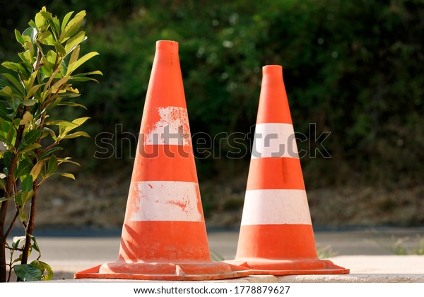 Orange traffic cones stand on the asphalt in a\
line, close-up.