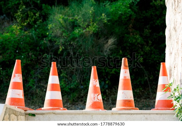 Orange traffic cones stand on the asphalt in a\
line, close-up.