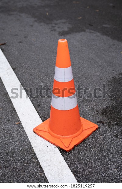 Orange\
traffic cones standing in a row on dark\
asphalt.