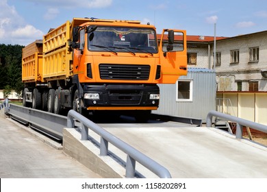 orange truck with grain is weighed on the scales in the grain storage area. Truck scales