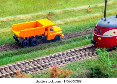 Orange truck on model train layout pass by passenger train