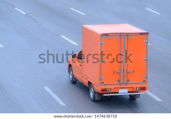Orange truck running on the road, small truck on\
the road.