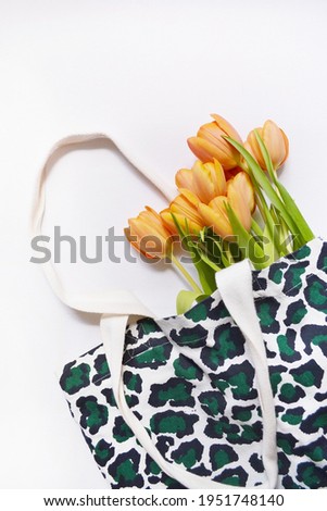 Orange tulips in the fabric bag on the white background. Tiger print. 
